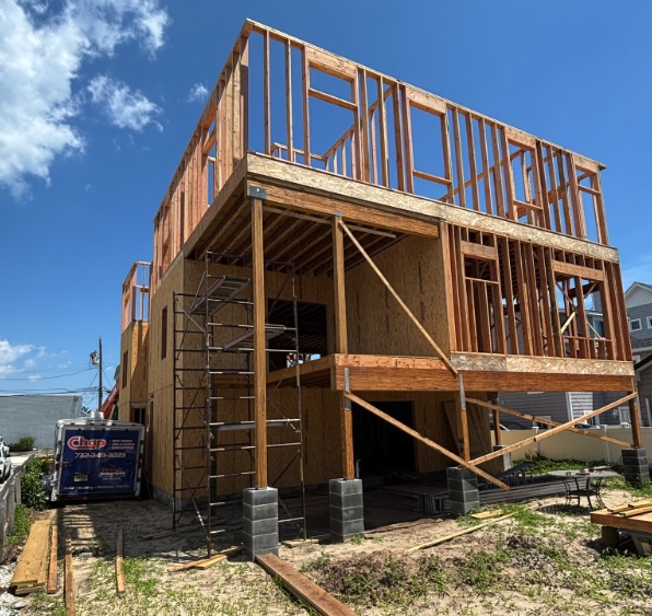 New custom home under construction in Seaside Heights, New Jersey by Chap Construction, featuring wood framing and structural work in progress under a clear summer sky.